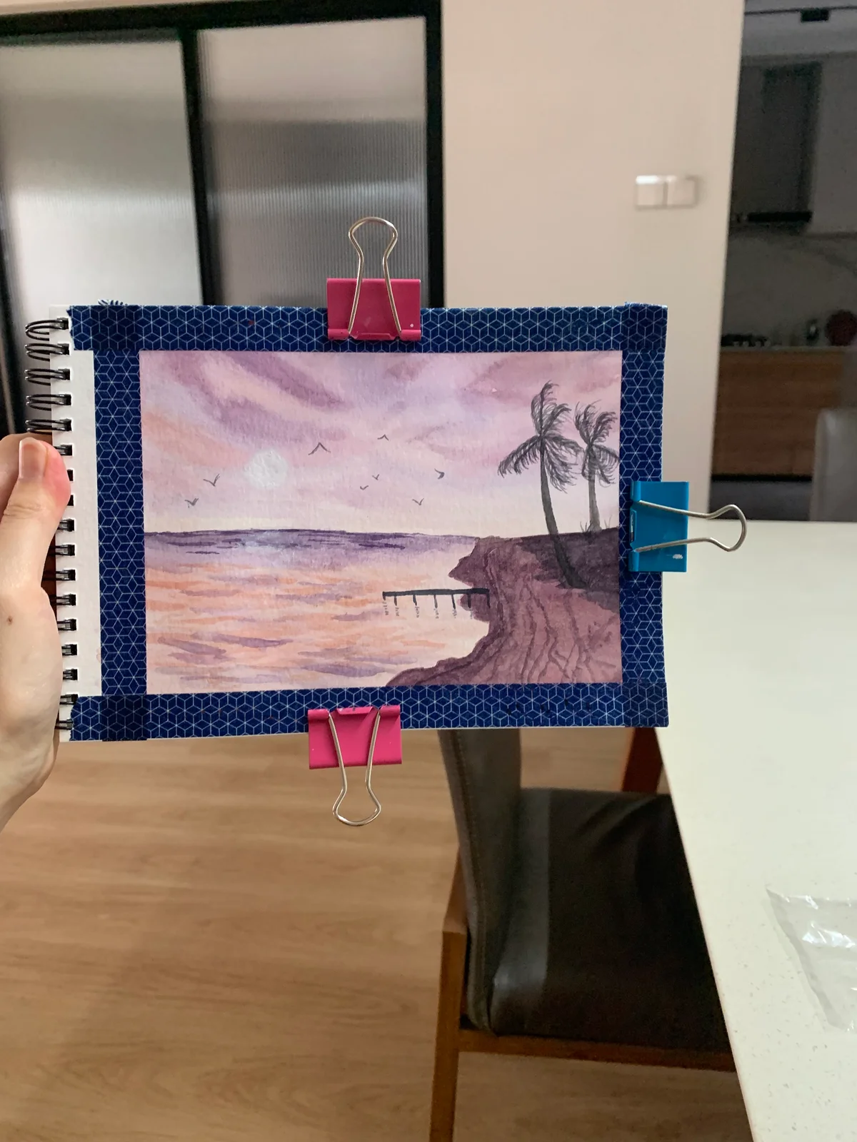 Sketchbook painting of palm trees and a beach at dusk in pink and violet tones.