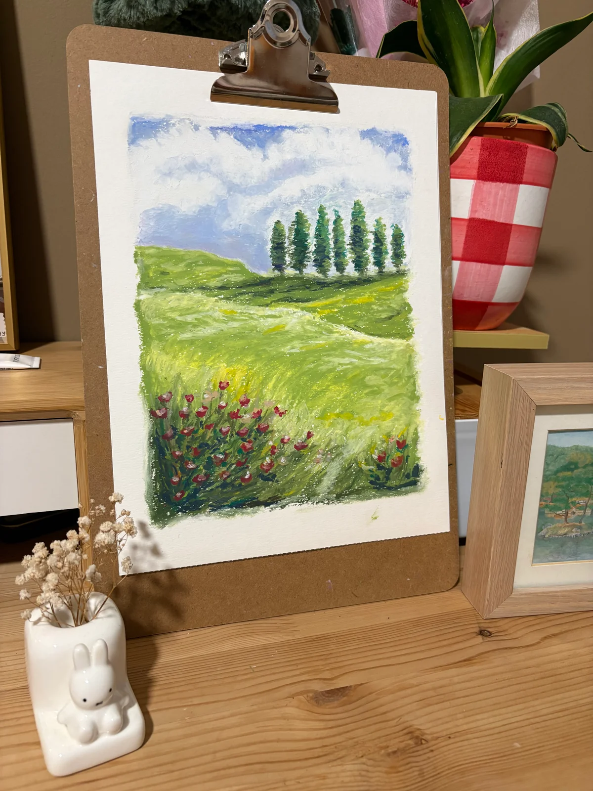 Painting of rolling green hills and a row of tall trees beneath a cloudy blue sky.